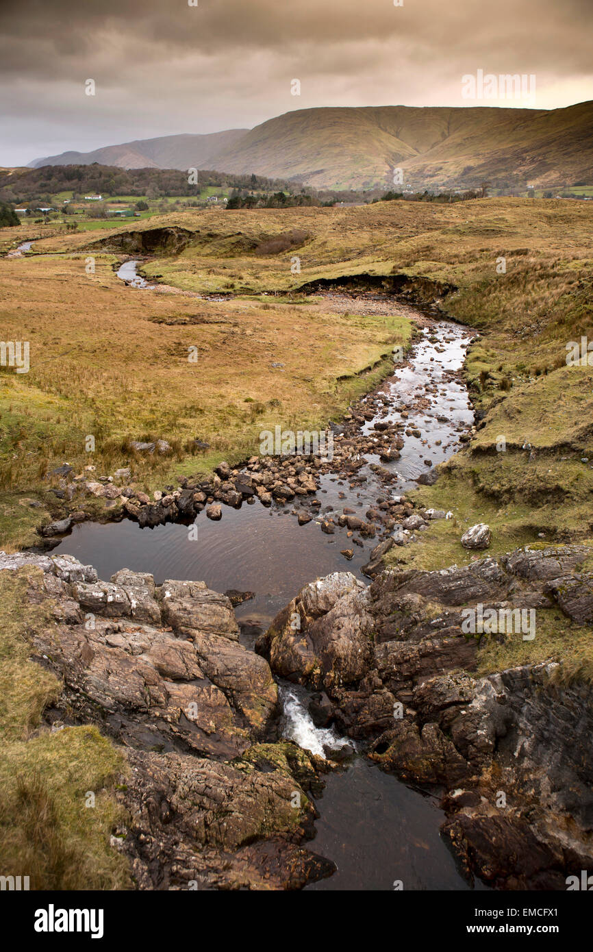 L'Irlande, Galway, le Connemara, Co Maumturk Mountains, un ruisseau qui traverse les terres marécageuses Banque D'Images