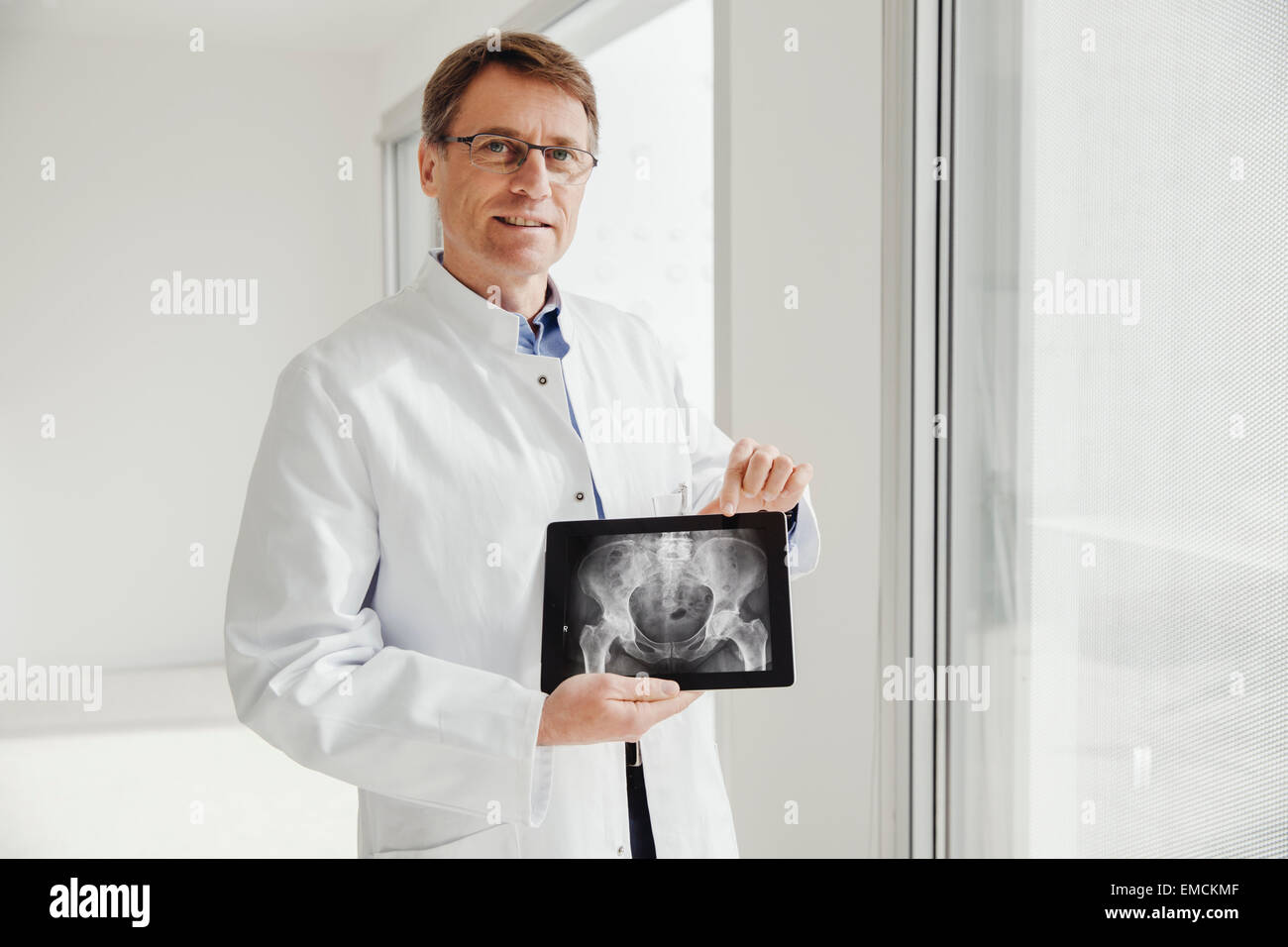 Man in lab coat présentant une radiographie scan sur sa tablette numérique Banque D'Images