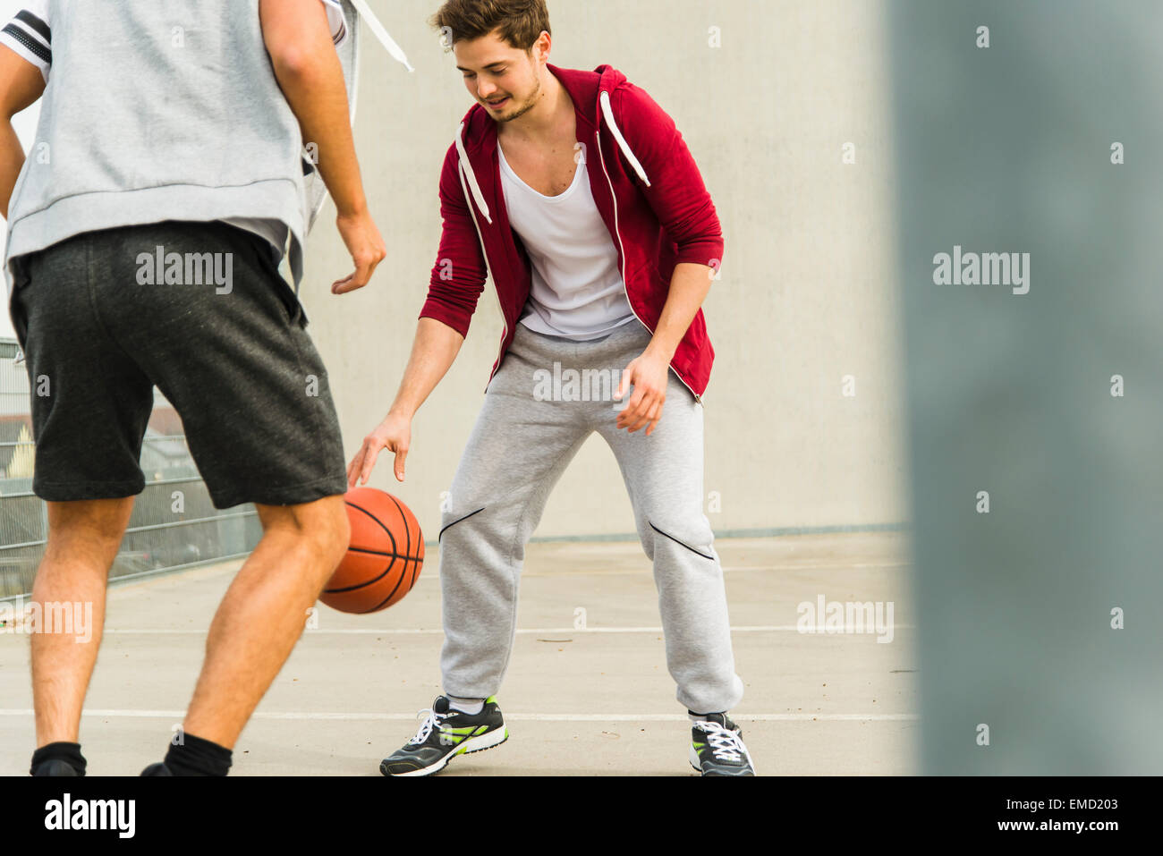 Deux jeunes hommes jouant au basket-ball sur niveau parking Banque D'Images