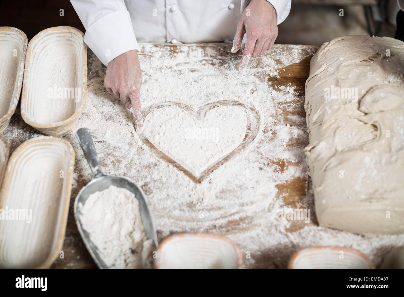 Dessin de coeur femme baker la farine sur une table en bois haut Banque D'Images