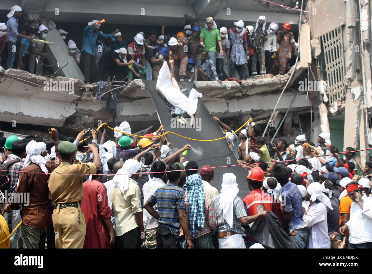 Les sauveteurs portent le corps d'une victime extrait des décombres de l'emplacement d'une usine de confection qui s'est effondré à Savar, Dhaka. Banque D'Images