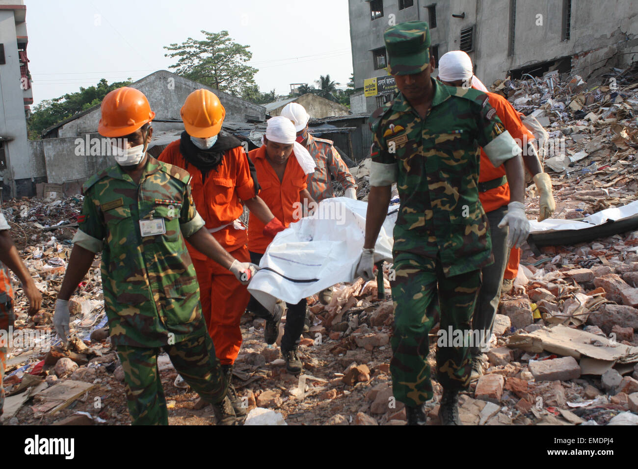 Les sauveteurs portent le corps d'une victime extrait des décombres de l'emplacement d'une usine de confection qui s'est effondré à Savar, Dhaka. Banque D'Images