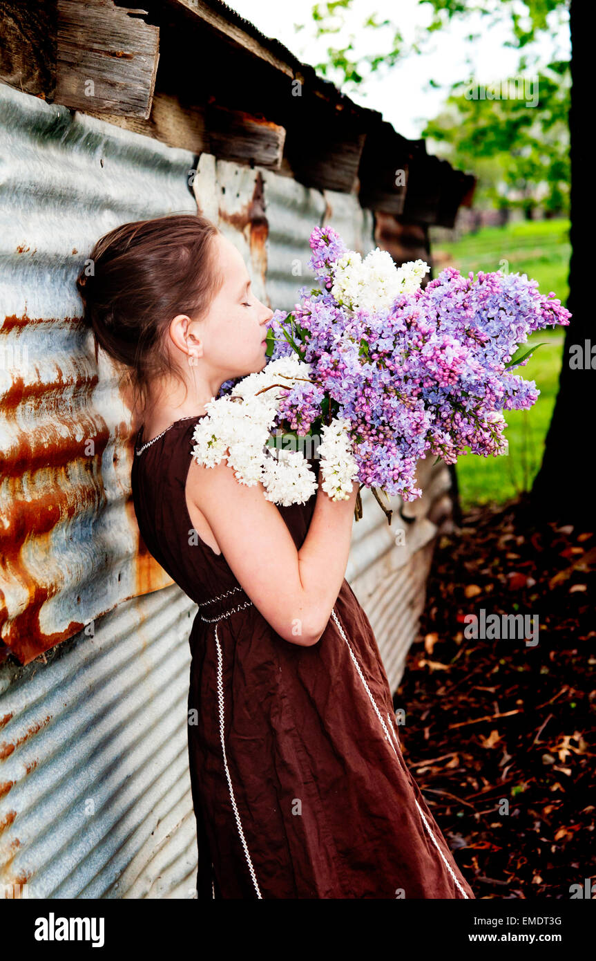 Girl smelling bouquet de lilas par barn Banque D'Images