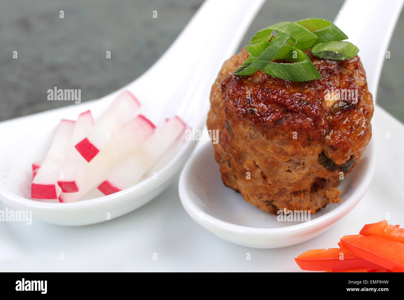 Meatball asiatique dans une cuillère de blanc avec garniture. Banque D'Images