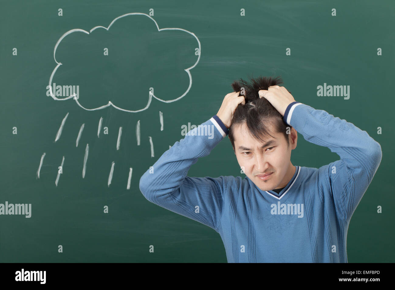Un gars avec une mauvaise humeur, dessiné sur un tableau noir et la pluie nuages Banque D'Images