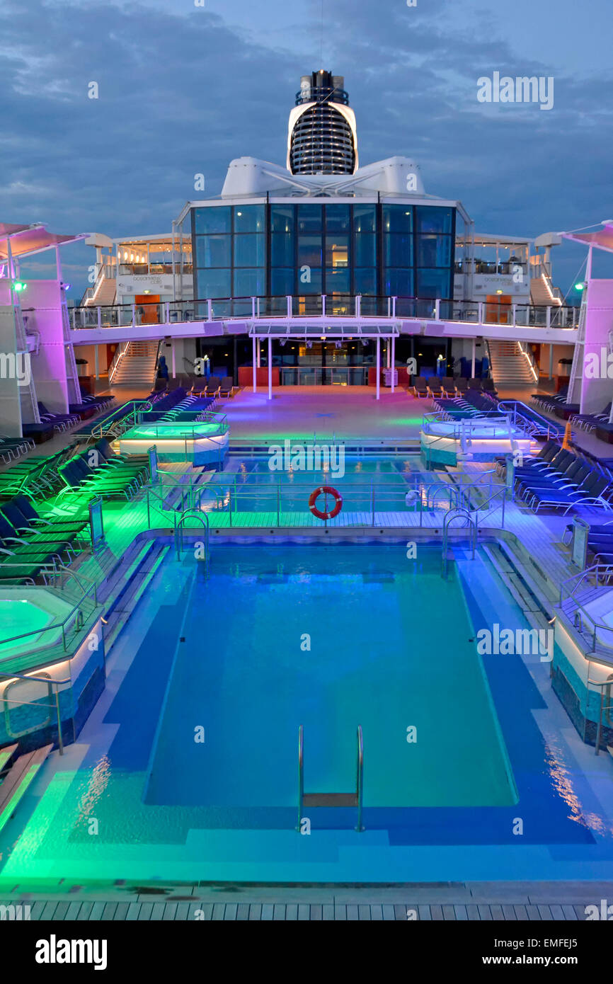 L'éclairage d'inondation on cruise ship plage de piscine à la fin de la journée avec des passagers sous le pont pour le repas du soir (pour voir de jour voir Alamy info le bord) Banque D'Images