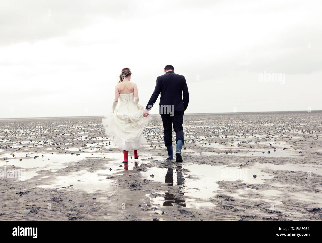 Mariée et le marié aller dans des bottes en caoutchouc à pied de la mer des Wadden Banque D'Images