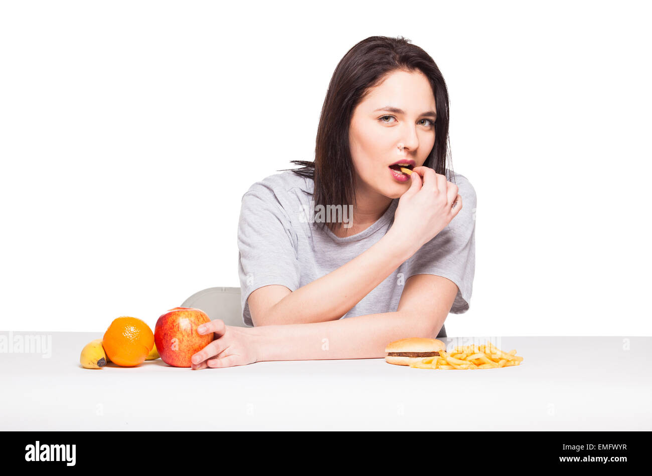 Par rapport à la malbouffe santé concept avec une femme naturelle dans les fruits avant d'attrape et repas avec hamburger frites, isolated on white Banque D'Images