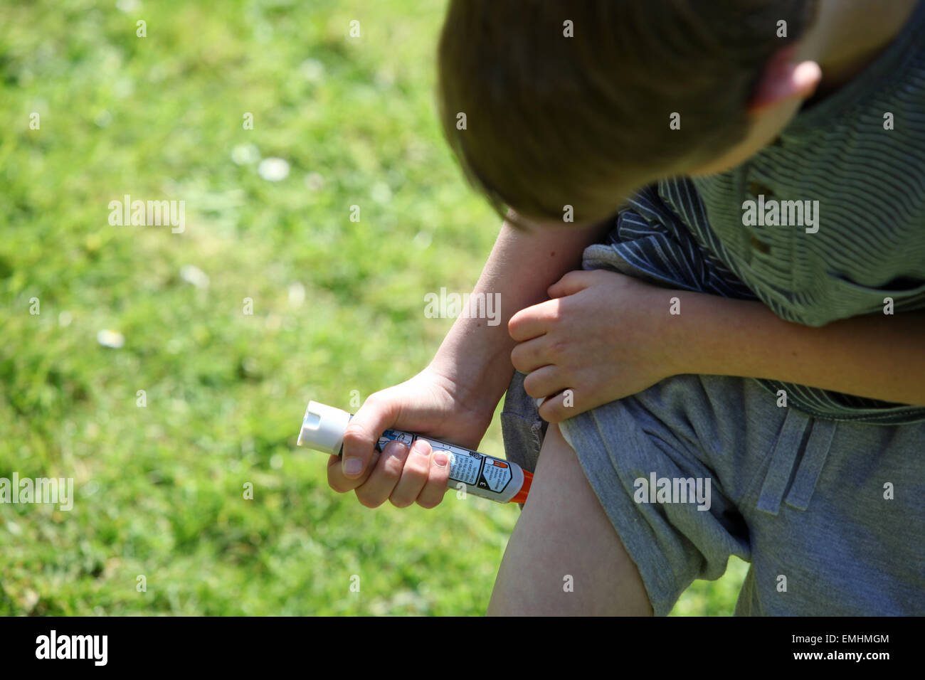 Un garçon à l'aide d'un Epipen dans sa cuisse démontrant que faire en cas d'un choc anaphylactique Banque D'Images