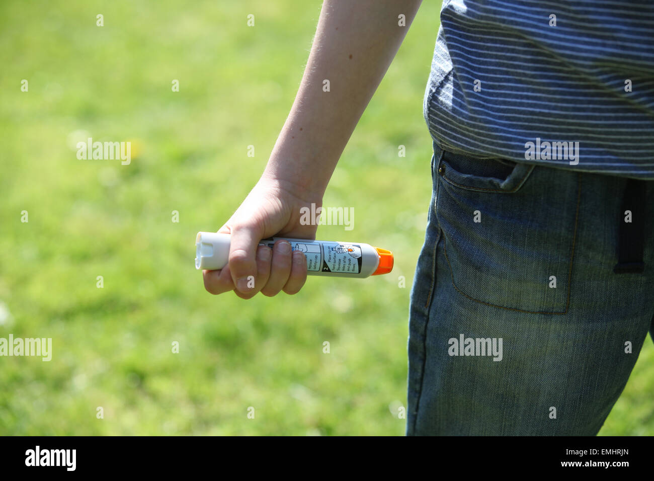 Un garçon à l'aide d'un Epipen dans sa cuisse démontrant que faire en cas d'un choc anaphylactique Banque D'Images