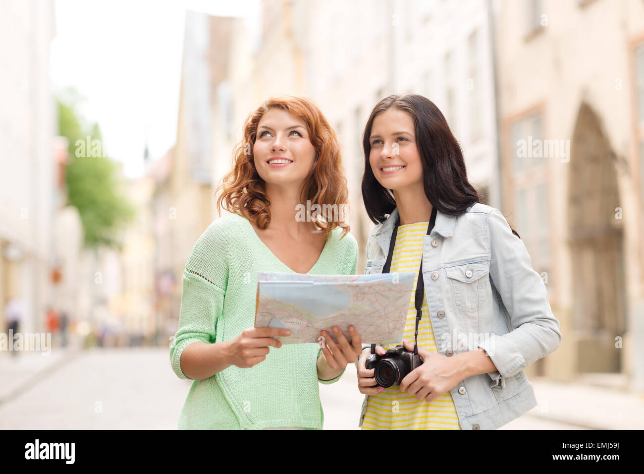 Smiling teenage girls avec la carte et l'appareil photo Banque D'Images