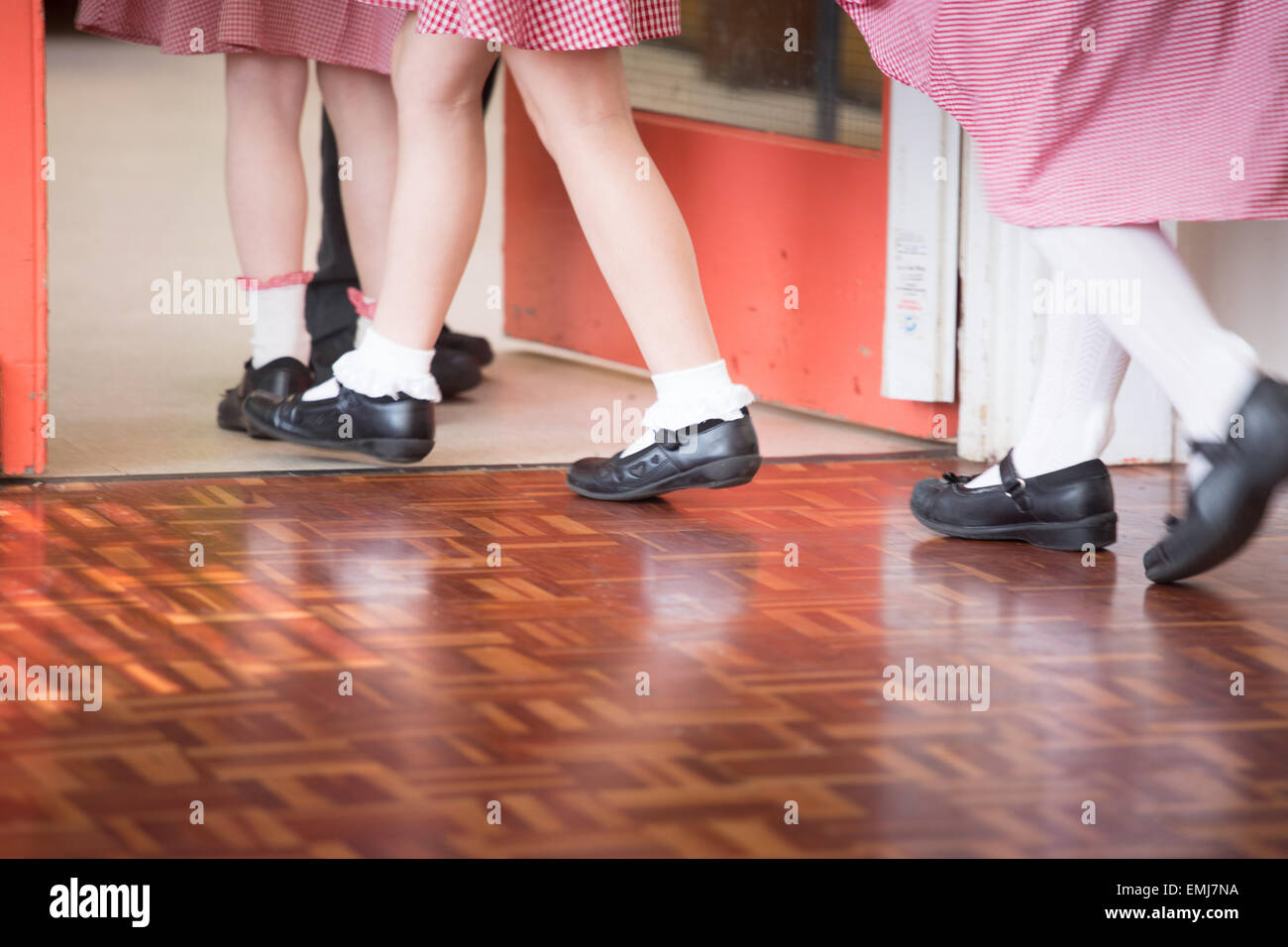 Un groupe d'écoliers britanniques quittent la salle d'école après - uniquement les jambes et pieds montrant. Banque D'Images