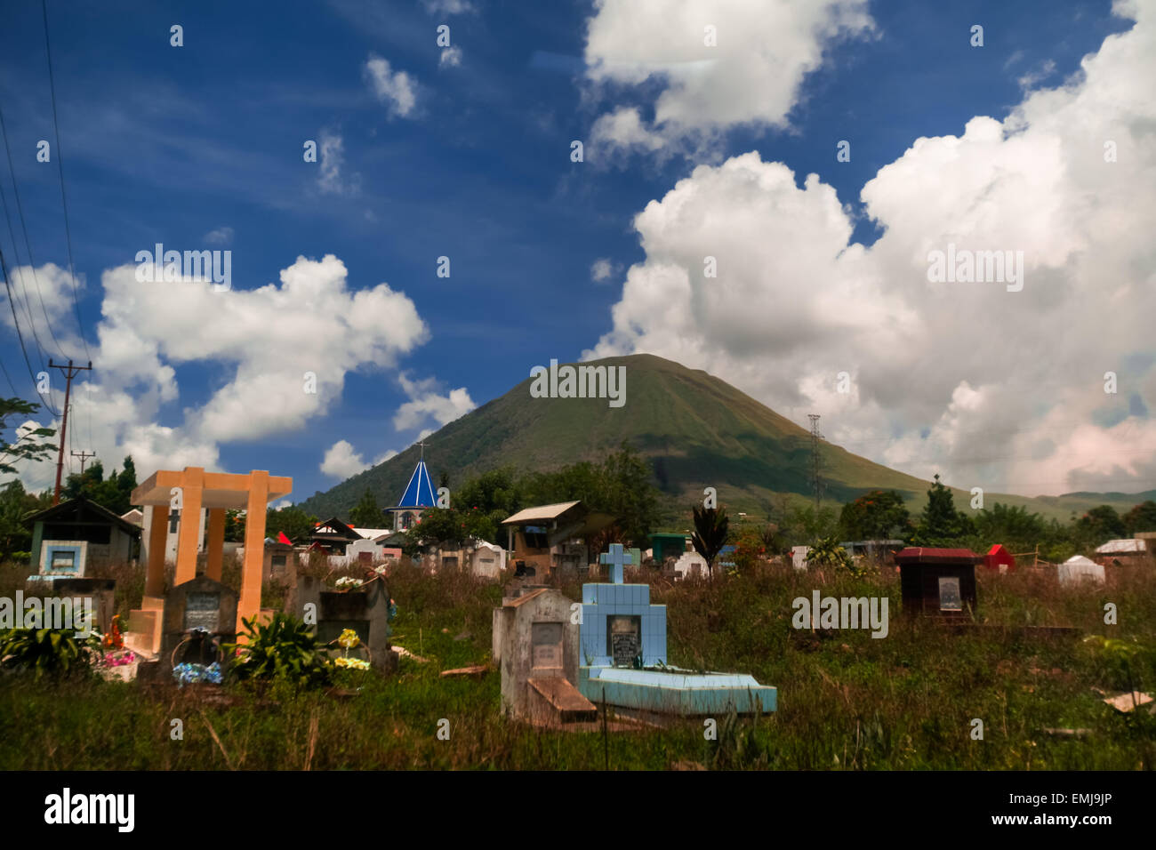 Un cimetière rural en arrière-plan du mont Lokon, volcan actif de Tomohon, au nord de Sulawesi, en Indonésie. Banque D'Images