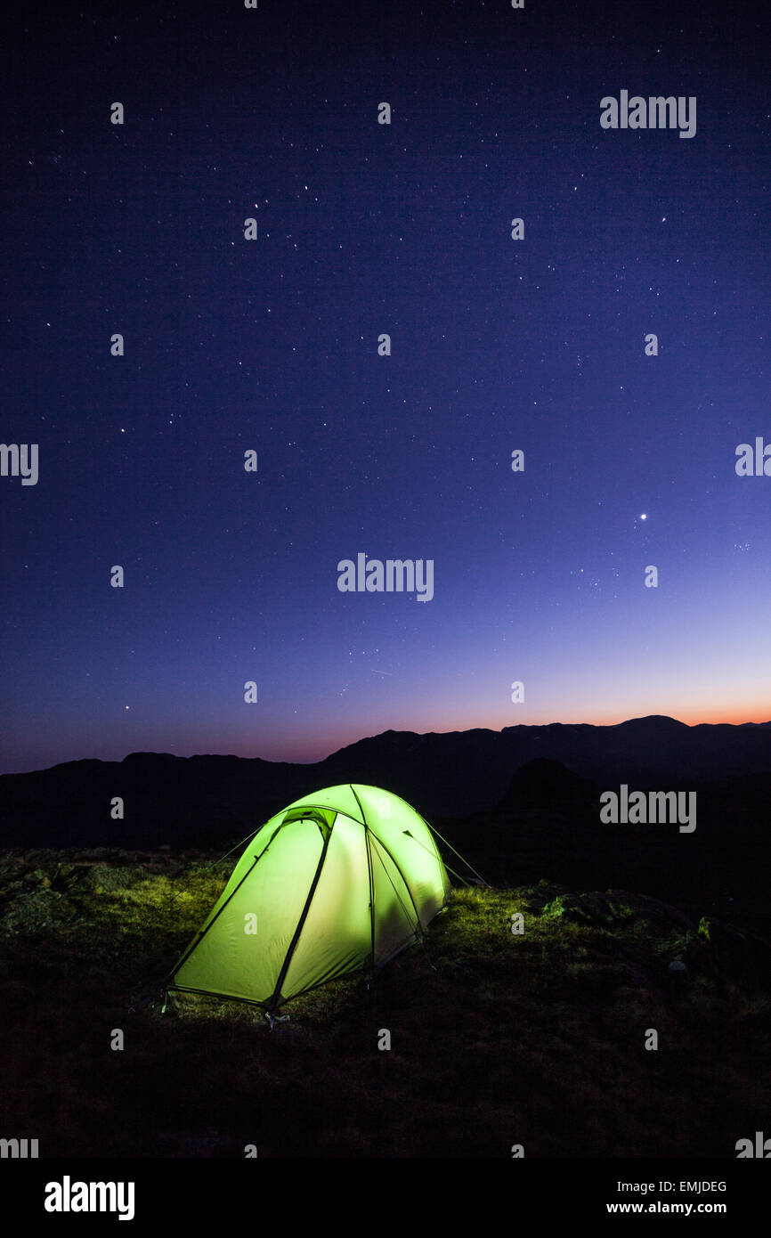 Tente camp sauvage flambeaux après le coucher du soleil comme les étoiles apparaissent dans le ciel sombre, elterwater, lake district Banque D'Images