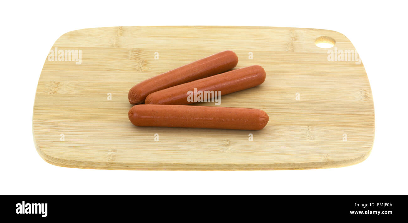 Trois toute la viande des hot dogs sur une planche à découper en bois isolé sur un fond blanc. Banque D'Images
