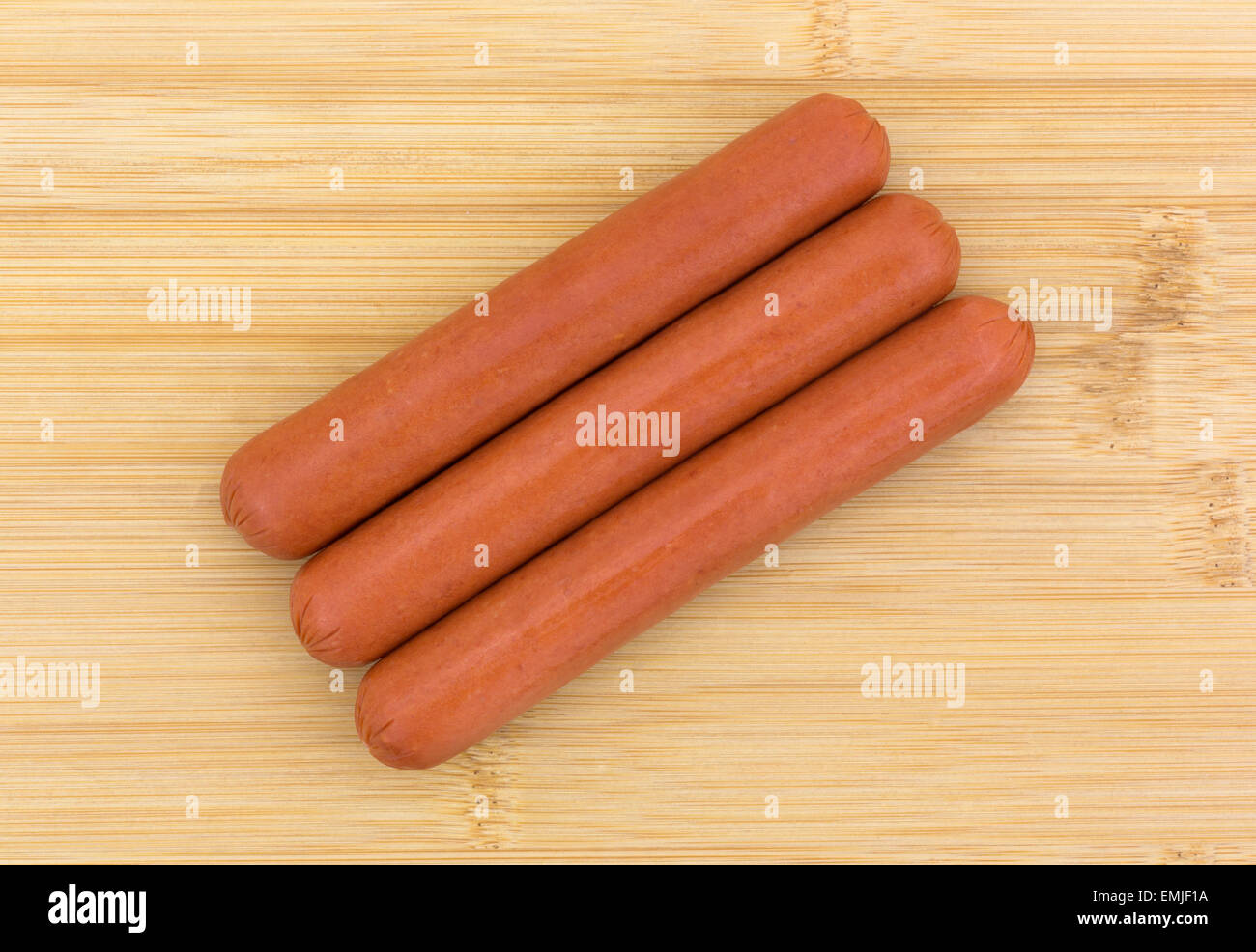 Vue du haut de trois tous les bovins de hot dog sur une planche à découper en bois. Banque D'Images