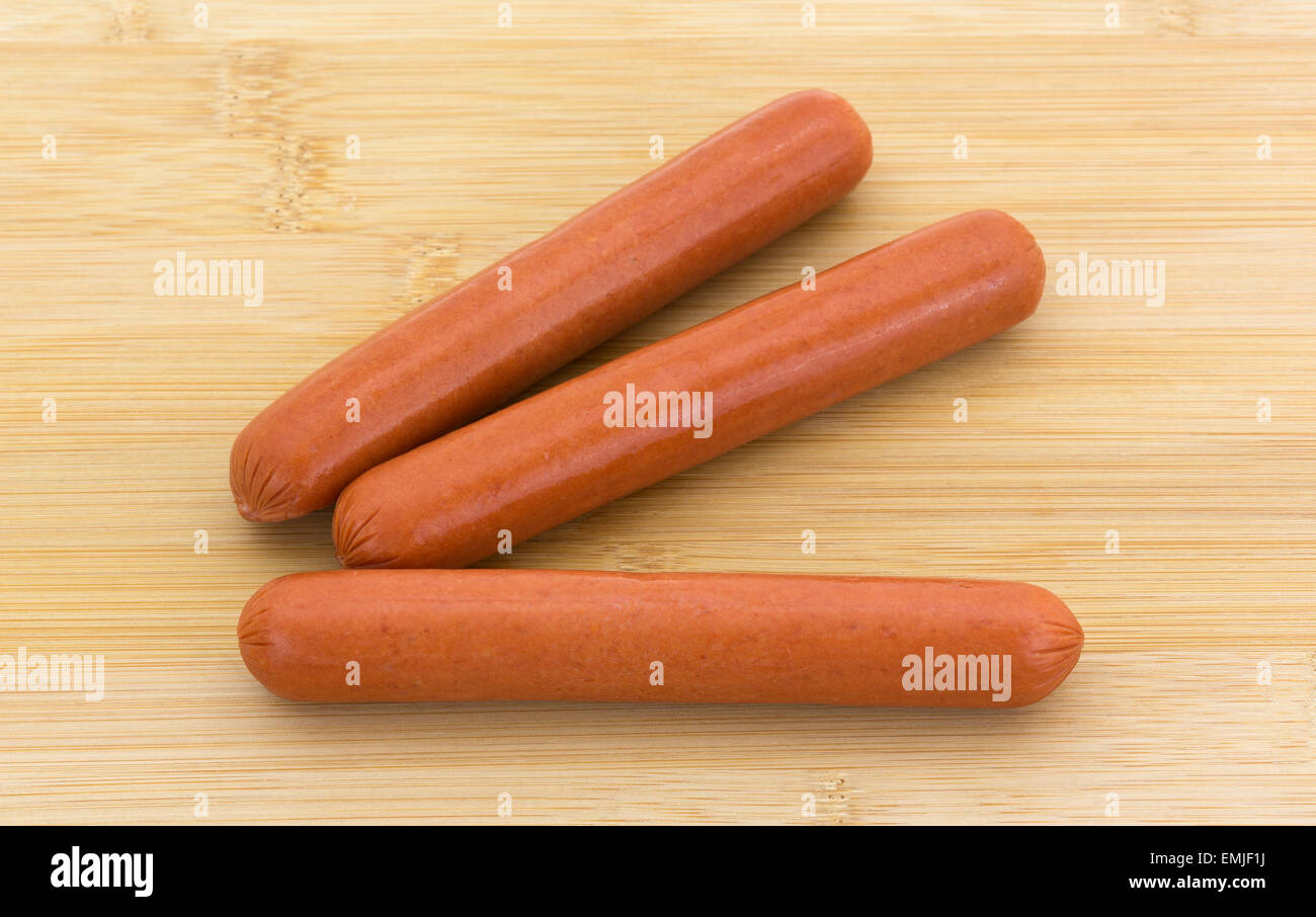 Trois toute la viande des hot dogs sur une planche à découper en bois. Banque D'Images