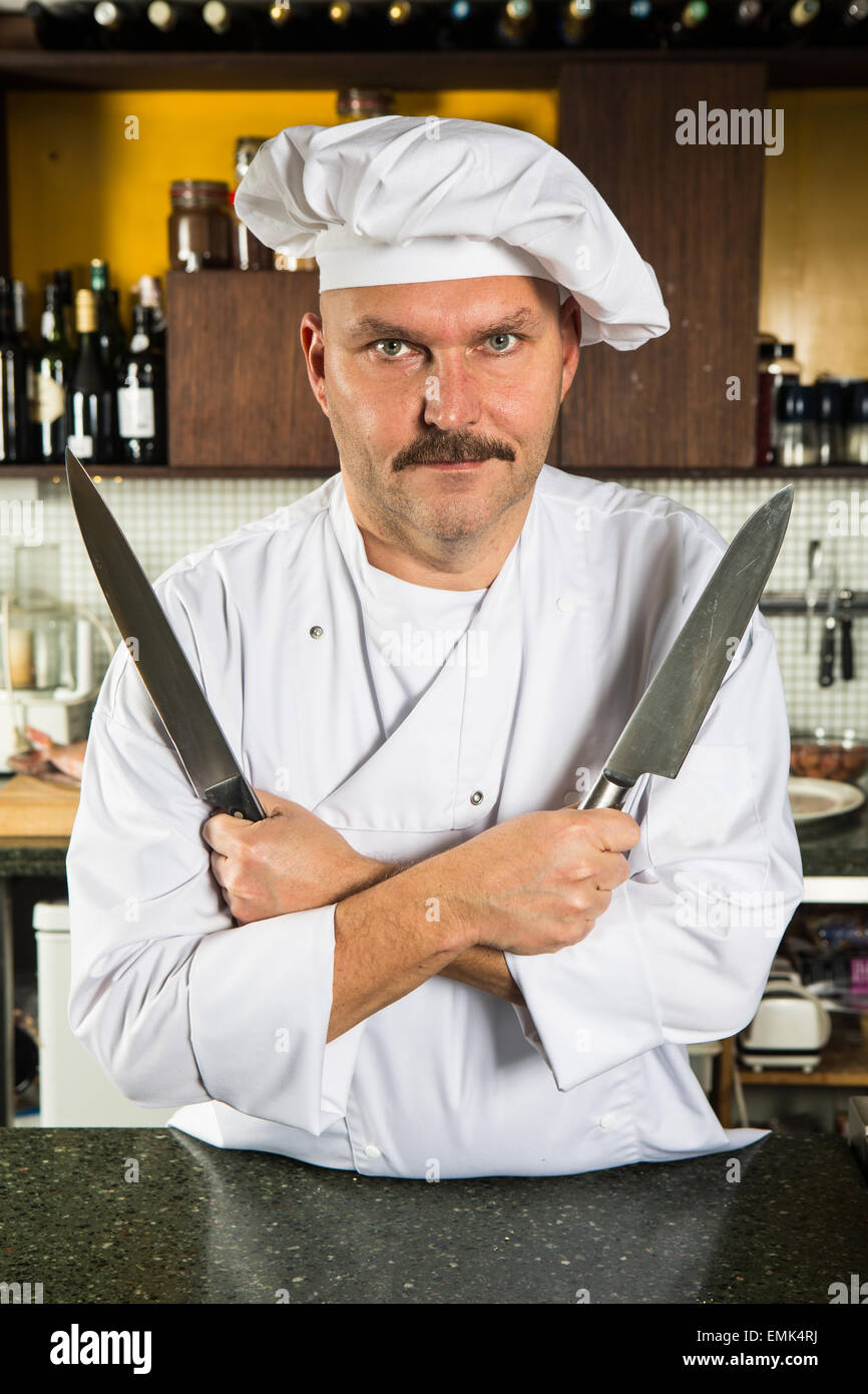 Mâle mature chef holding deux couteaux dans ses mains Banque D'Images