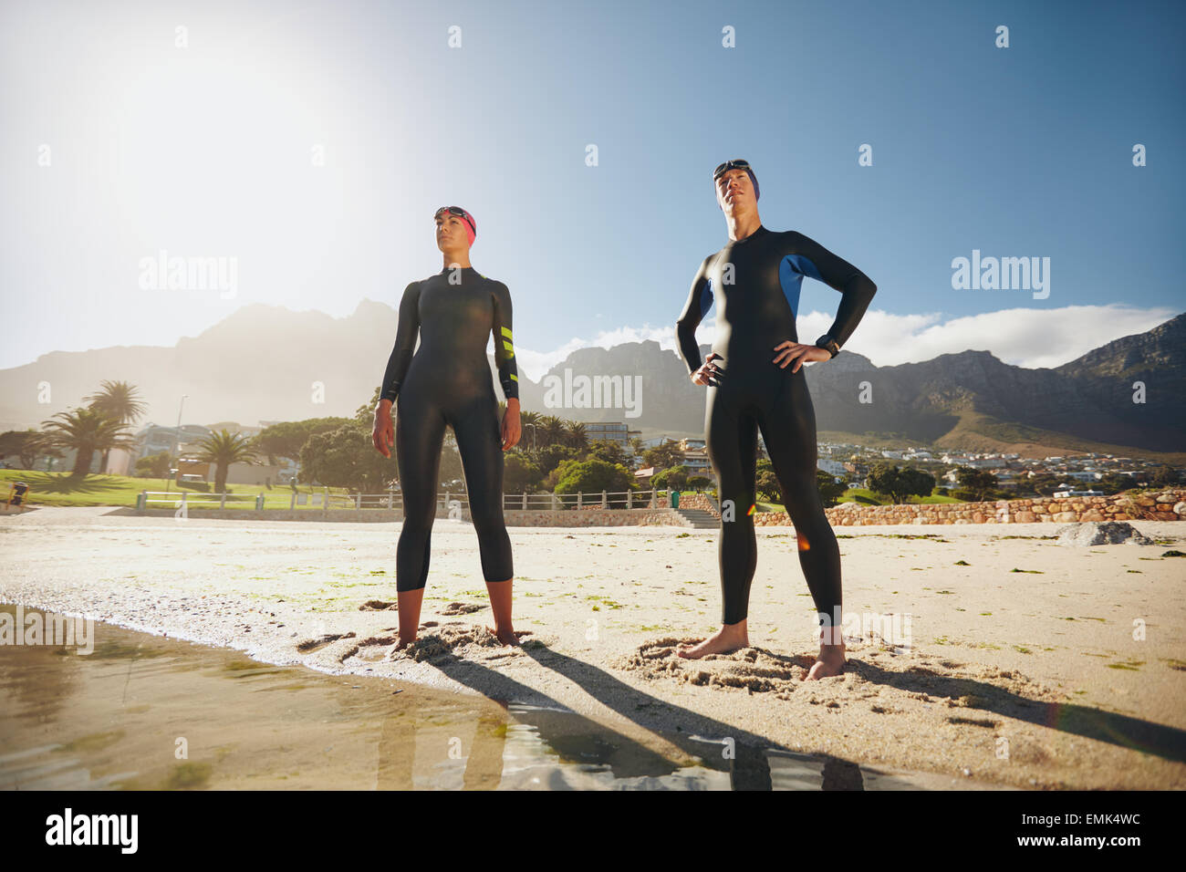 Portrait of a déterminé les triathlètes, hommes et femmes à la recherche dans la distance. Jeune homme et femme debout à la plage wearin Banque D'Images Portrait of a déterminé les triathlètes, hommes et femmes à la recherche dans la distance. Jeune homme et femme debout à la plage wearin Banque D'Images