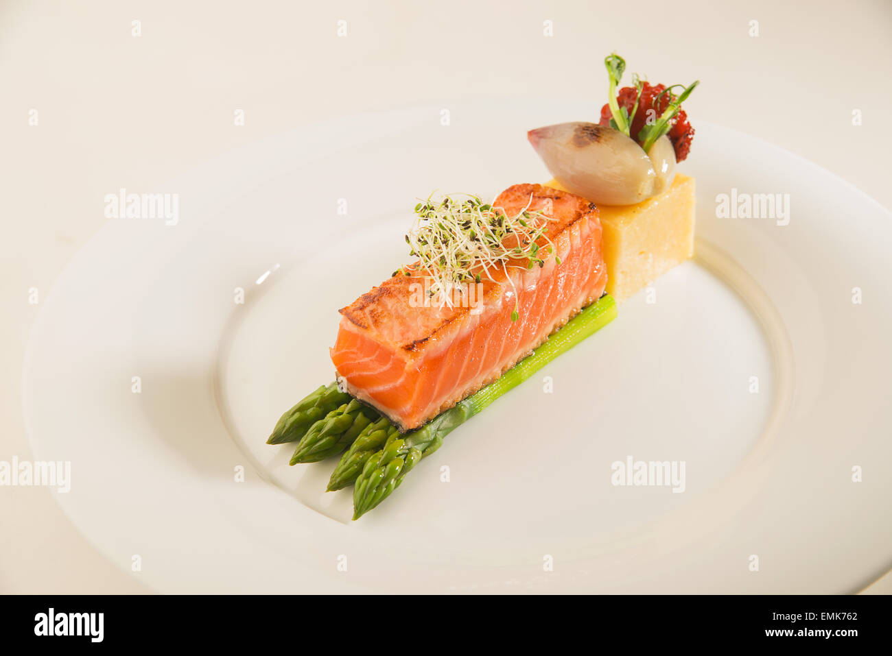 Un morceau de saumon poêlé, asperges, maïs bouillie sur une plaque blanche Banque D'Images