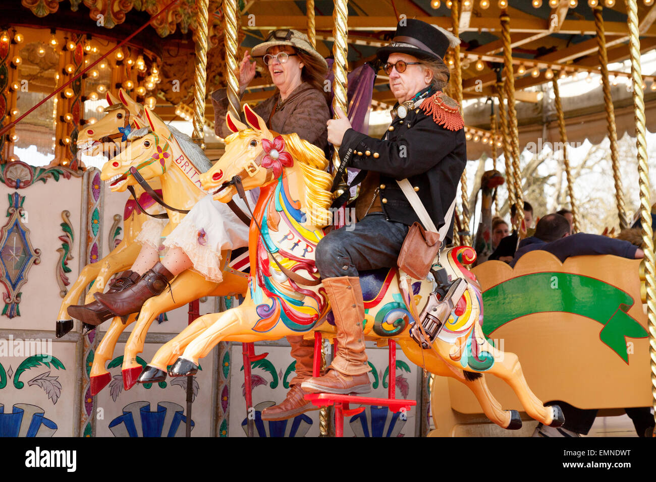 Couple d'âge moyen s'amusant sur un rond-point ou carrousel, Norfolk, UK Banque D'Images