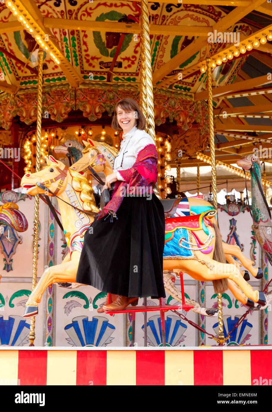 Middle aged woman age de 50s de 50 ans s'amusant sur un rond-point ou carrousel, Norfolk, UK Banque D'Images