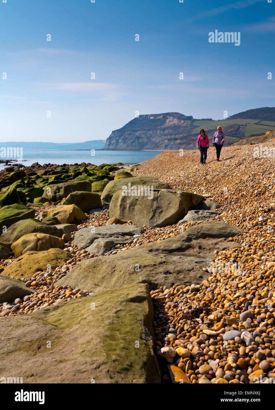 Deux femmes marchant sur la plage en face de Golden Cap falaise à Seatown sur la côte jurassique du Dorset Ouest en Angleterre Banque D'Images