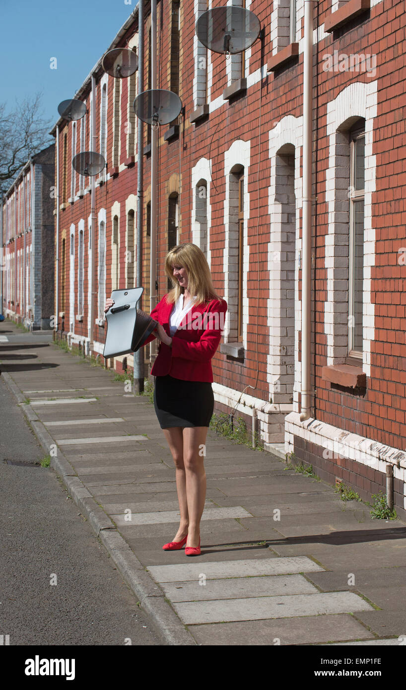 Businesswoman carrying briefcase le long d'une rue résidentielle de maisons mitoyennes à Port Talbot au Pays de Galles du sud Banque D'Images