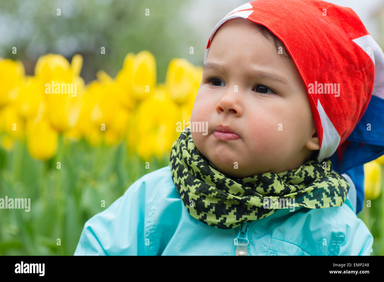 Belle petite fille avec un champ de tulipes en arrière-plan Banque D'Images