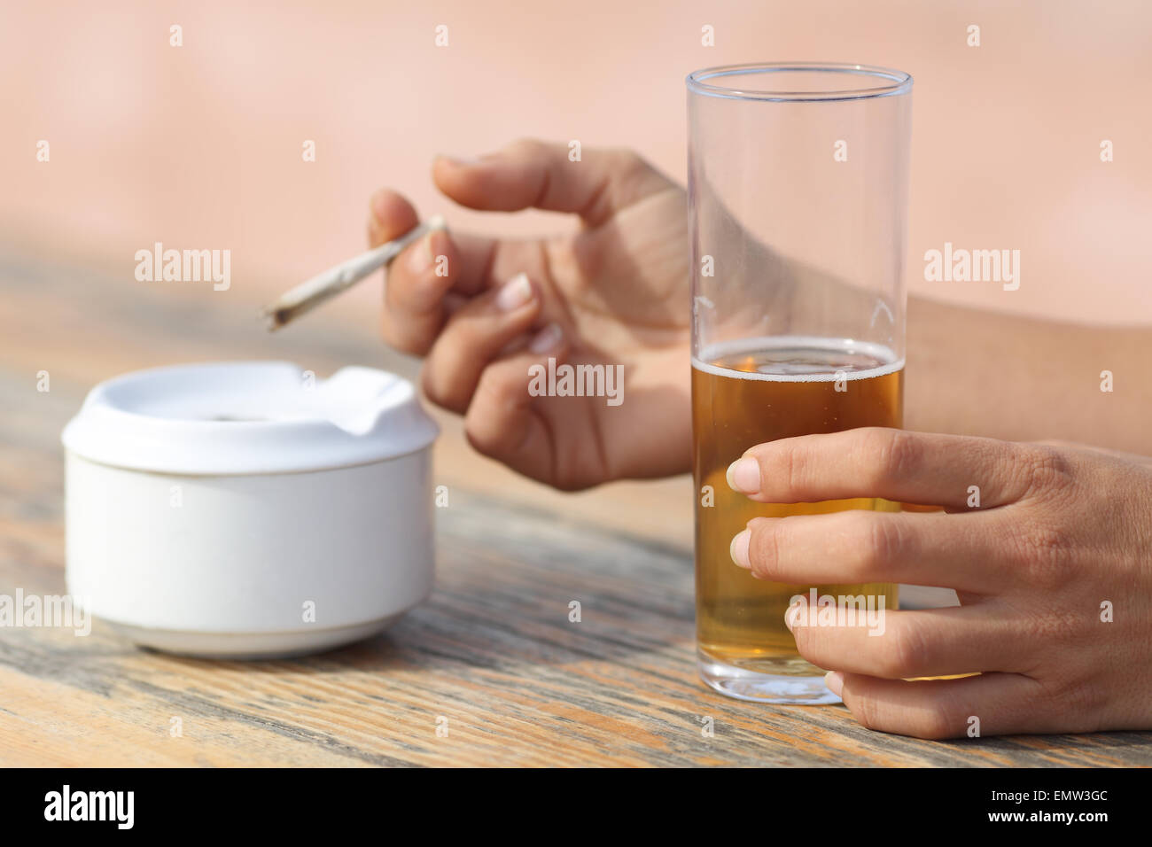 Femme mains tenant une cigarette fumer et boire de l'alcool dans un bar table Banque D'Images