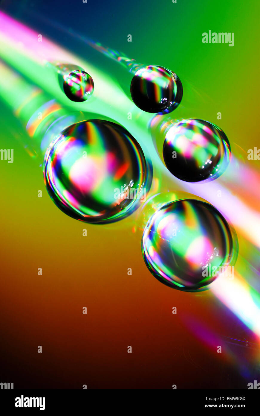 Gouttes d'eau sur un CD avec les réfractions de la lumière effet arc-en-ciel Banque D'Images