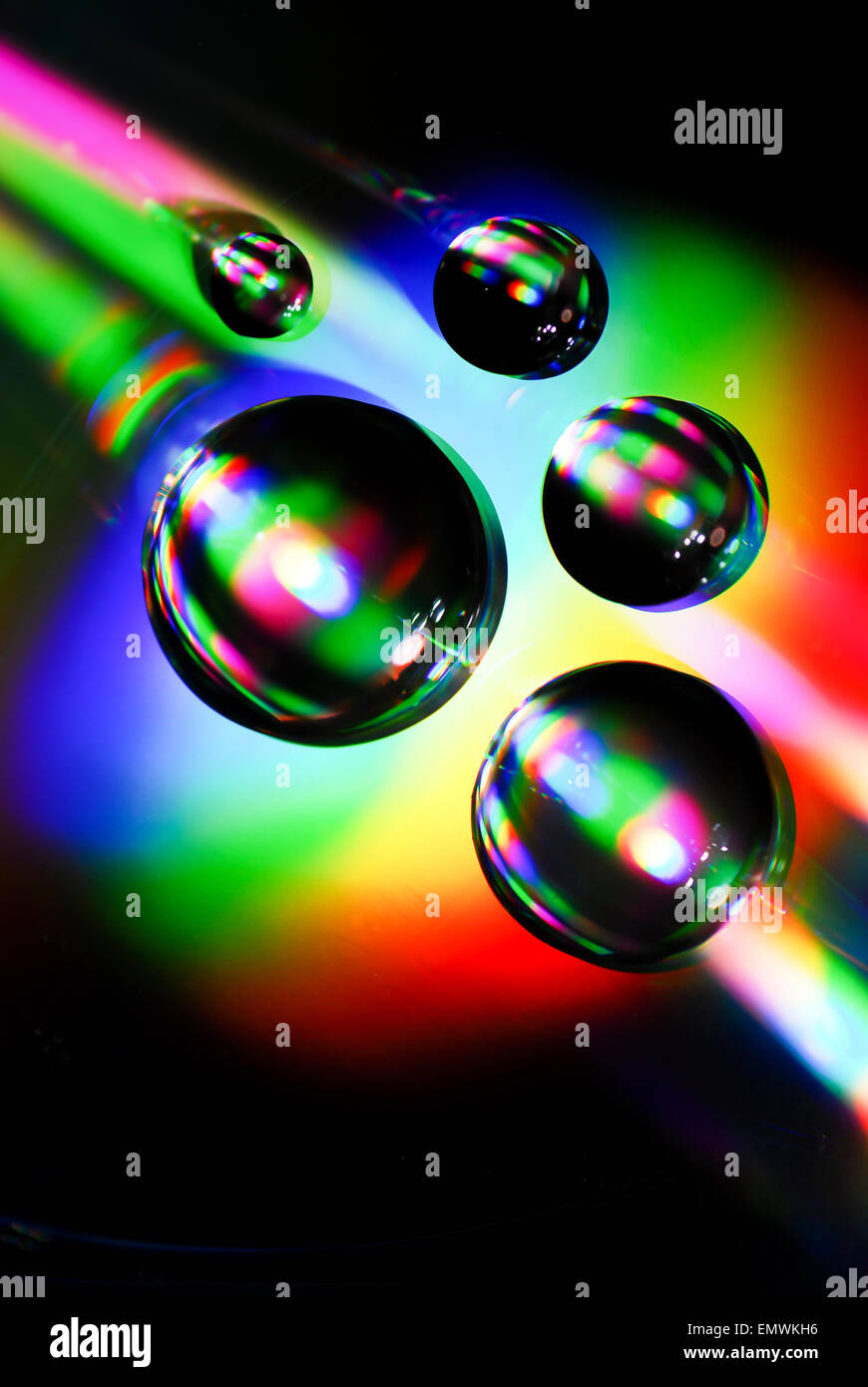 Gouttes d'eau sur un CD avec les réfractions de la lumière effet arc-en-ciel Banque D'Images