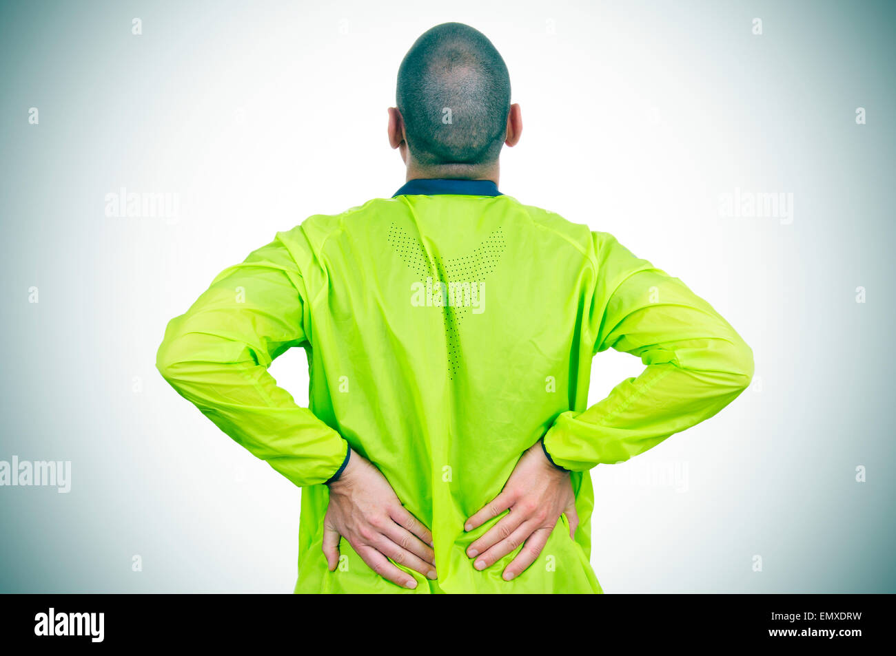 Un jeune sportif de race blanche portant des vêtements de sport avec ses mains dans son dos à cause de ses douleurs au bas du dos Banque D'Images