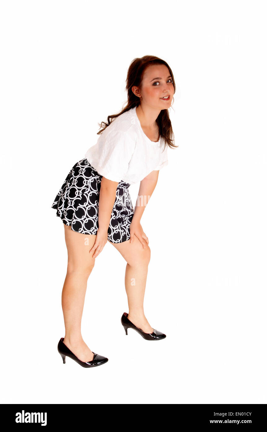 Une jolie fille adolescente dans un chemisier blanc et jupe courte isolés pour fond blanc, flexion vers le bas. Banque D'Images