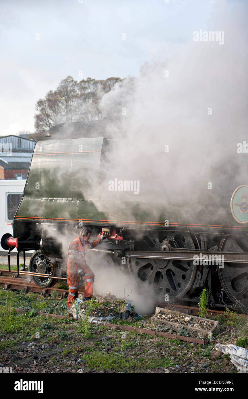 Membre de l'équipe de soutien d'examiner la locomotive à vapeur 'Tangmere' au cours d'un arrêt de maintenance à Eastbourne, Royaume-Uni Banque D'Images