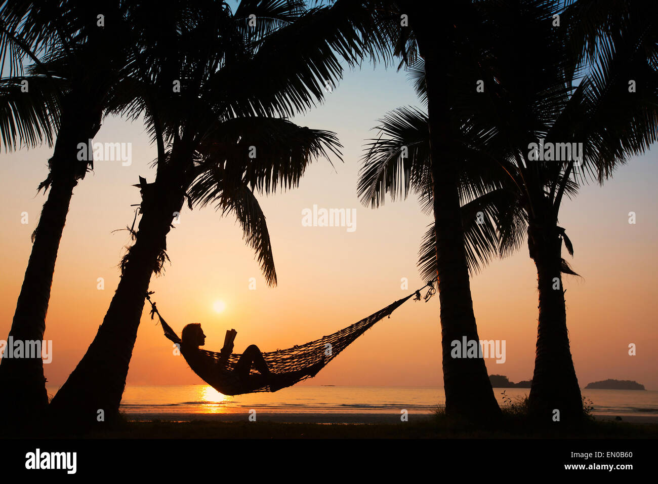 Les vacances à la plage, silhouette of woman reading in hammock Banque D'Images Les vacances à la plage, silhouette of woman reading in hammock Banque D'Images