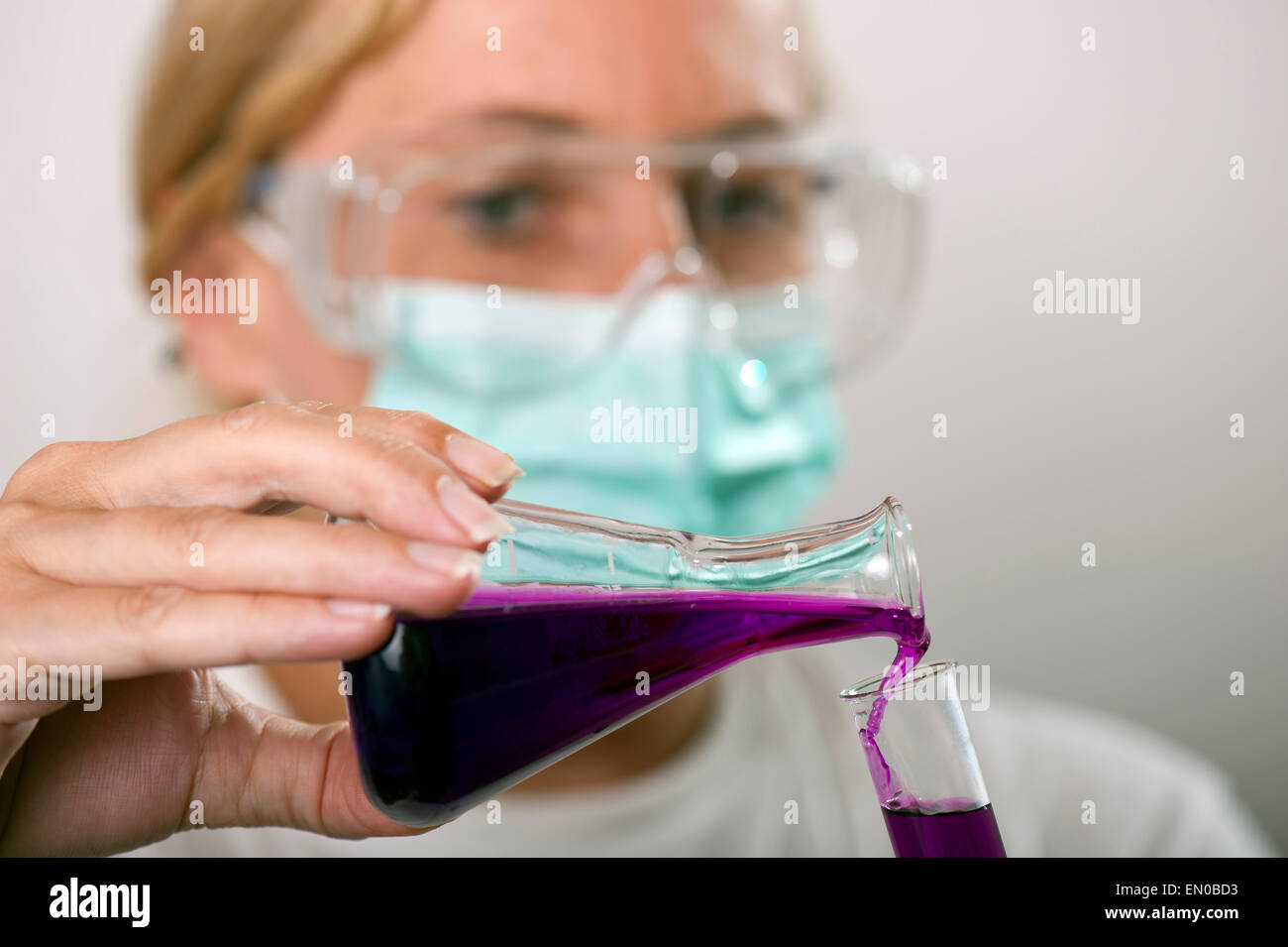 Chimiste verser dans un flacon de liquide dans un tube à essai Banque D'Images