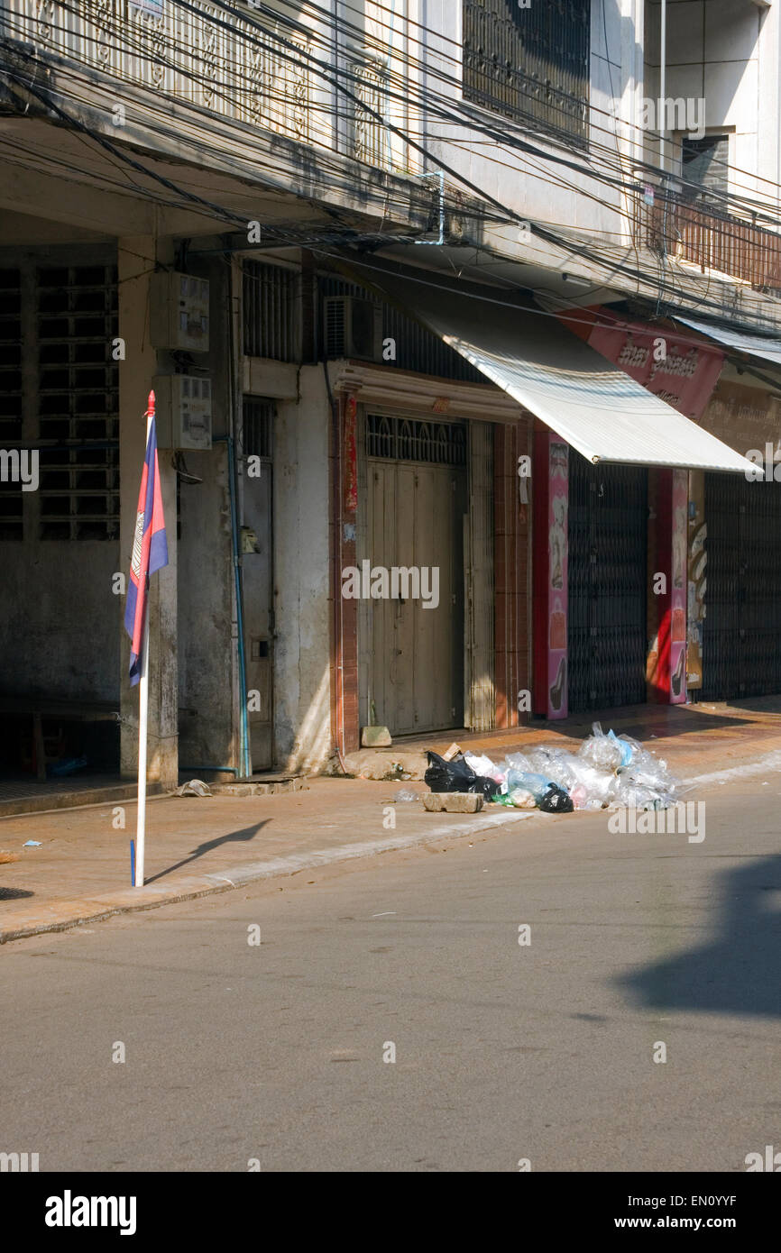 Un drapeau cambodgien est affiché près d'une pile d'ordures ménagères d'une cité déserte rue de Kampong Cham, au Cambodge. Banque D'Images