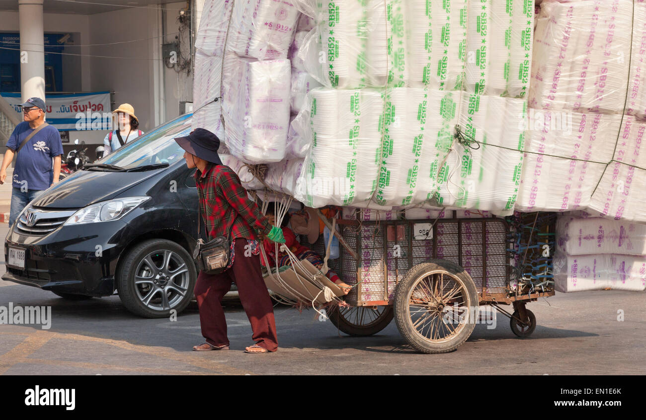 Chiang Rai, Mae Sae, poste frontière avec la Birmanie, Myanmar. Le nord de la Thaïlande. Négociant paysanne se débat avec un énorme panier de biens Banque D'Images