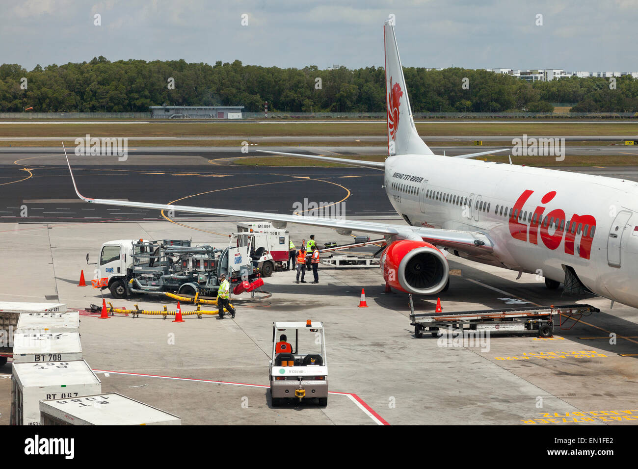 Boeing 737-900ER, en piste, le personnel de l'entretien de l'aéroport passagers chargement assurance dans un avion tenir à l'aide d'une courroie transporteuse Banque D'Images