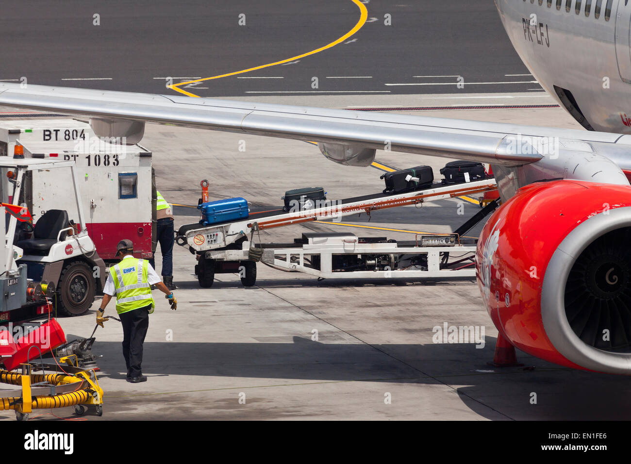 Du côté de l'air, l'entretien, le personnel de l'aéroport passagers chargement assurance dans un avion tenir à l'aide d'une courroie transporteuse Banque D'Images