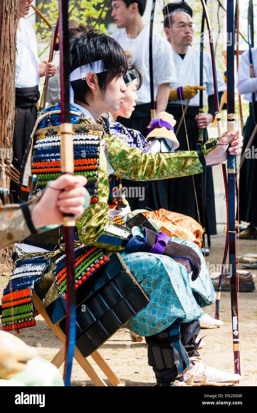 Jeune homme assis à l'extérieur tout en habillé comme un archer Samurai de la période Kamakura, tenant l'arc de shigetou, pendant un concours de tir à l'arc. Banque D'Images