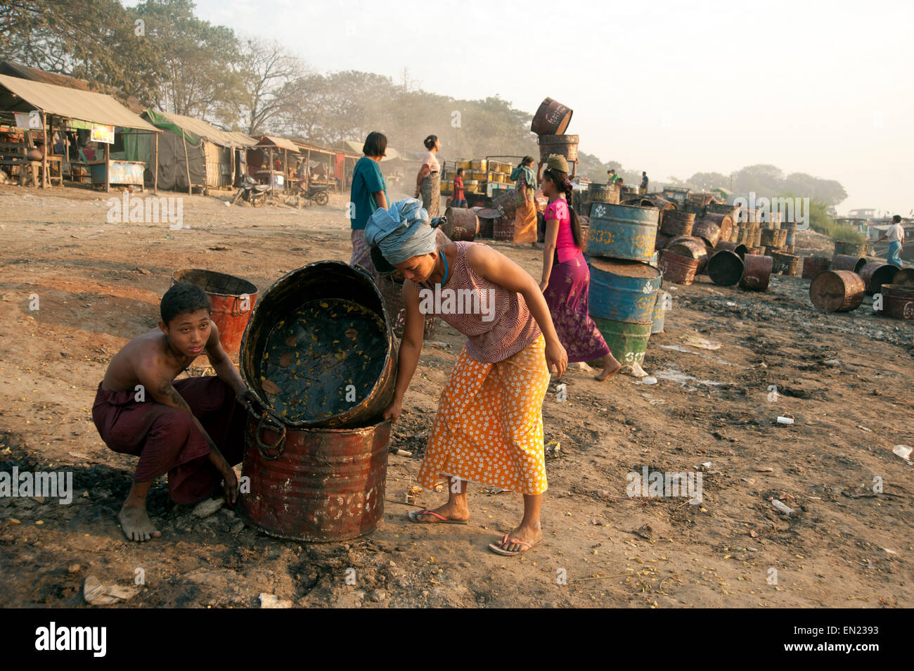 Ouvriers birmans soulevant des fûts d'oli vides sur l'Ayeyarwady rive à mandalay myanmar Banque D'Images