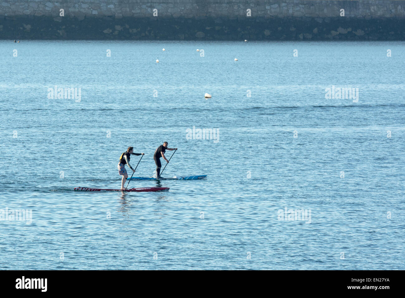 Deux personnes paddleboarding sur soirée ensoleillée Banque D'Images