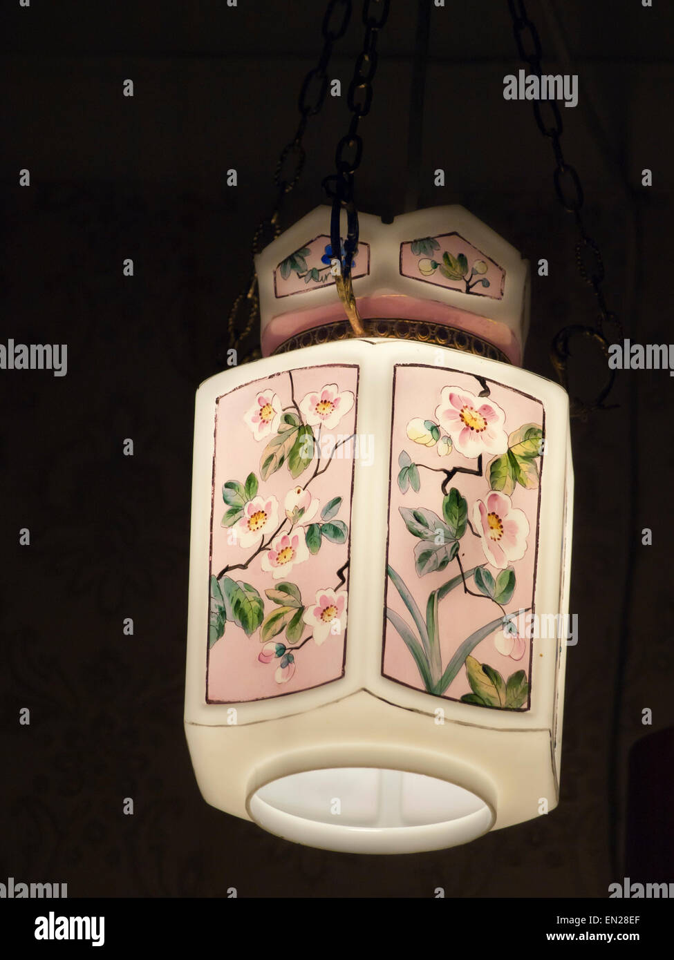 Lampe lanterne de verre coloré avec motif de fleurs de style chinois illumine le coin d'une pièce sombre Banque D'Images