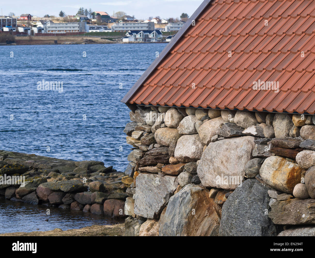 Ancien hangar à bateaux avec des murs en pierre avec des logements modernes dans la distance, Stavanger Norvège Hafrsfjord Banque D'Images