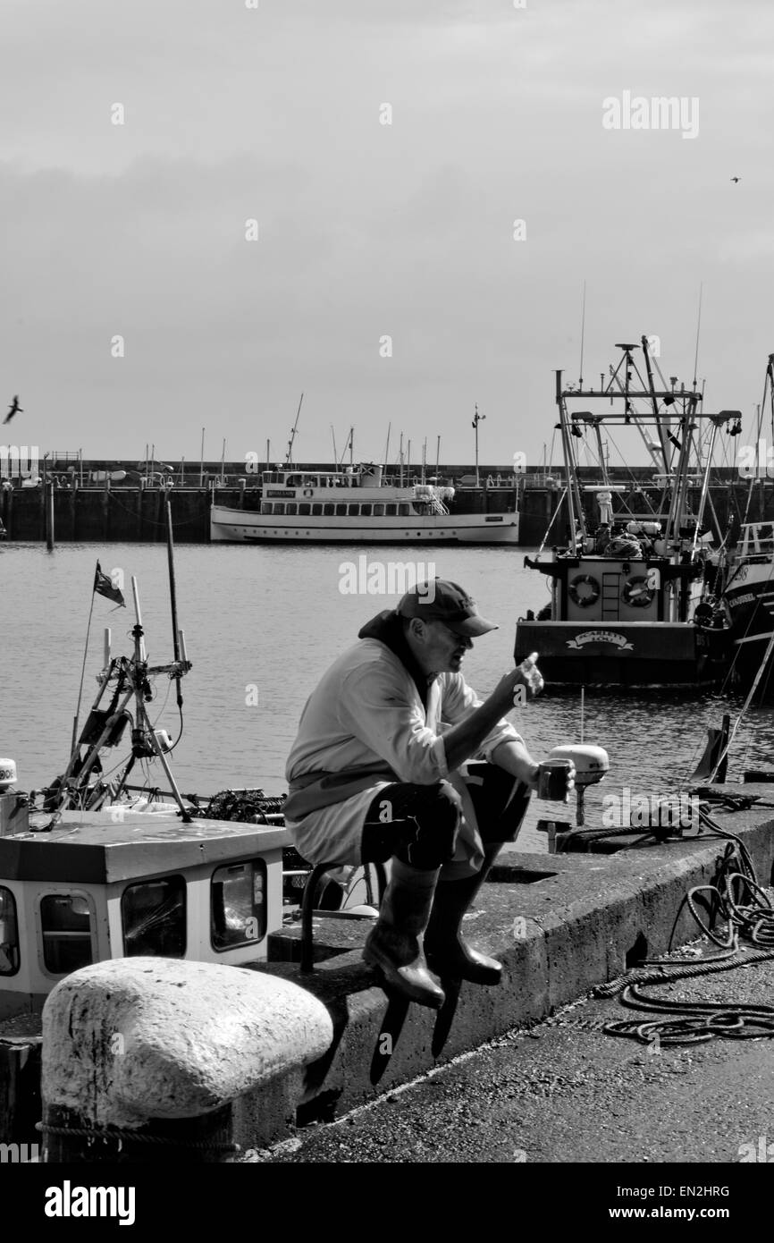 Ad noir blanc image documentaire montrant un pêcheur profitant de son repas sur une journée chaude à Scarborough Banque D'Images