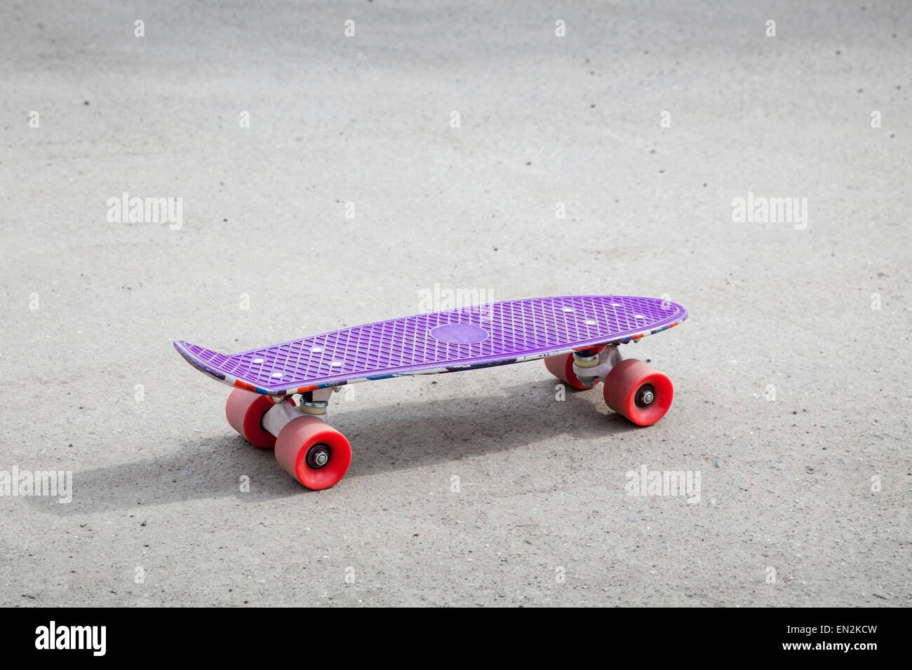 Petite taille violet moderne skateboard en plastique vide sur une route asphaltée en milieu urbain Banque D'Images