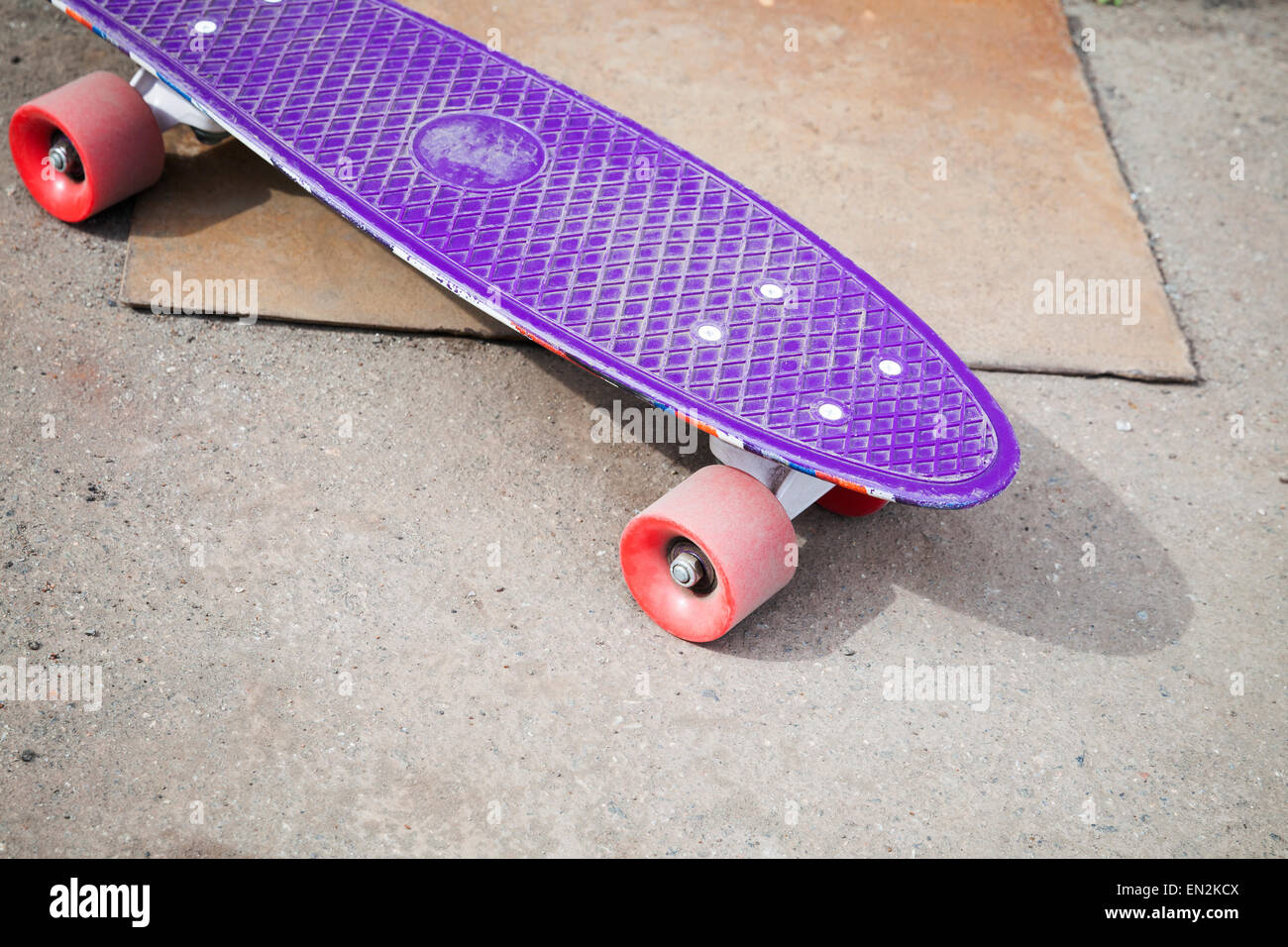 Petite taille en plastique violet moderne skateboard, repose sur une chaussée urbaine d'asphalte Banque D'Images