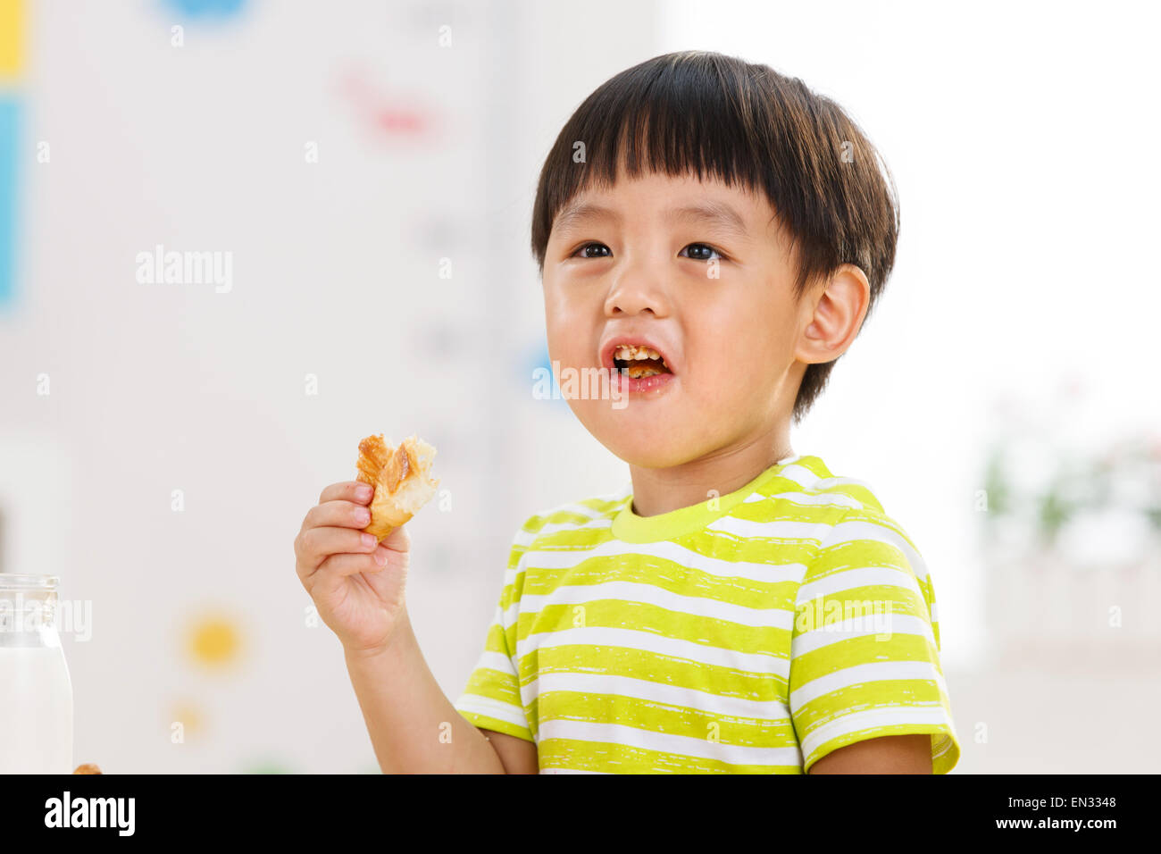 Le petit garçon mange du pain dans le jardin d'enfants Banque D'Images